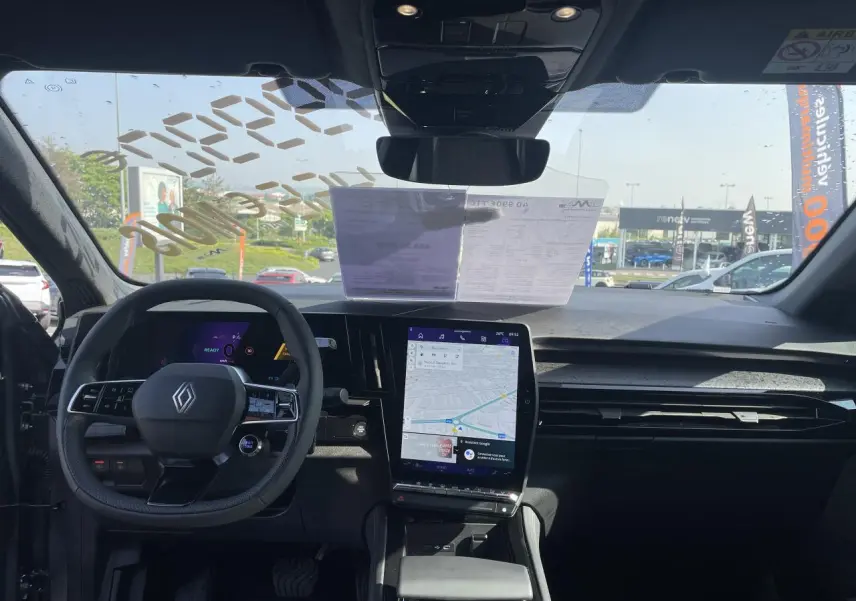 Vue intérieure avant du Renault Rafale 2025, tableau de bord noir avec écran tactile vertical affichant la navigation.