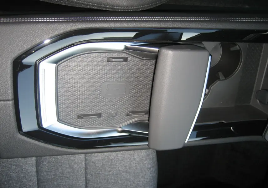 Gros plan sur la console centrale noire du Renault Austral 2025, mettant en valeur le chargeur sans fil et l'accoudoir.