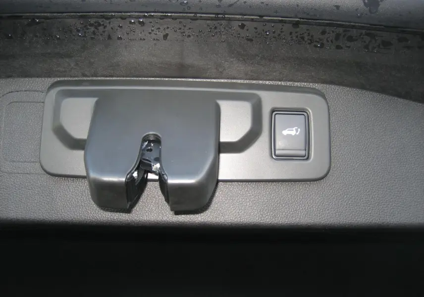 Gros plan sur le mécanisme de verrouillage et le bouton d'ouverture électrique du hayon du Renault Austral bleu outremer.