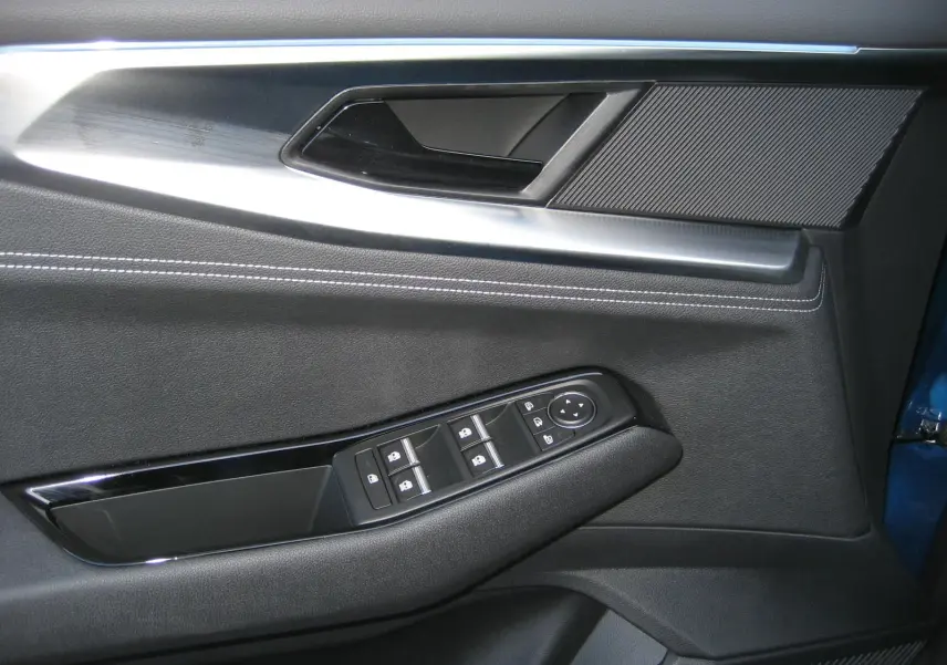 Détail de la porte côté gauche du Renault Austral 2025 bleu outremer, montrant les commandes des vitres et la poignée intérieure.