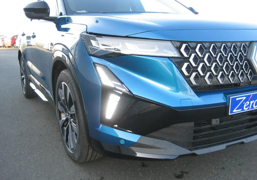 Vue 3/4 avant gauche du Renault Austral bleu outremer avec toit noir, mettant en valeur sa calandre hexagonale et ses feux LED distinctifs.