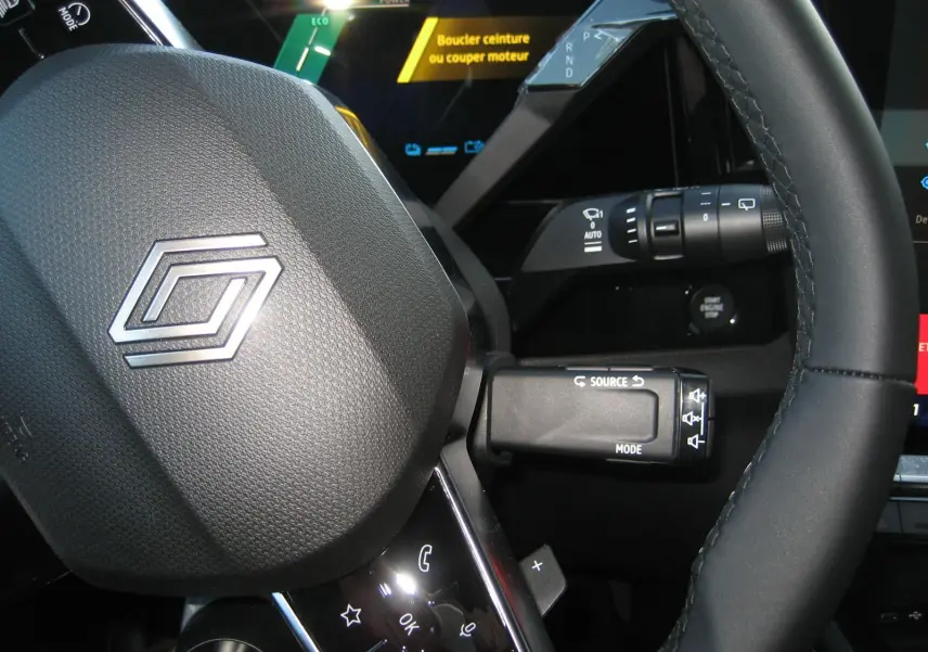 Gros plan sur le volant et les commandes du tableau de bord du Renault Austral PH.2, affichage digital avec message de sécurité.