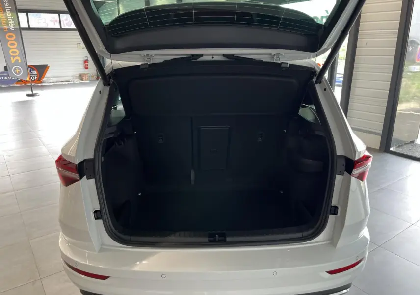 Vue arrière du coffre ouvert d'un SUV SKODA KAROQ blanc 2025 dans un showroom lumineux.