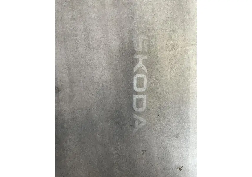 Projection lumineuse du logo SKODA au sol sur fond gris, sans véhicule visible.