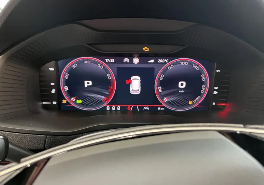 Vue rapprochée du tableau de bord digital du Skoda Karoq 2025, affichage en mode parking avec compteurs rouges.