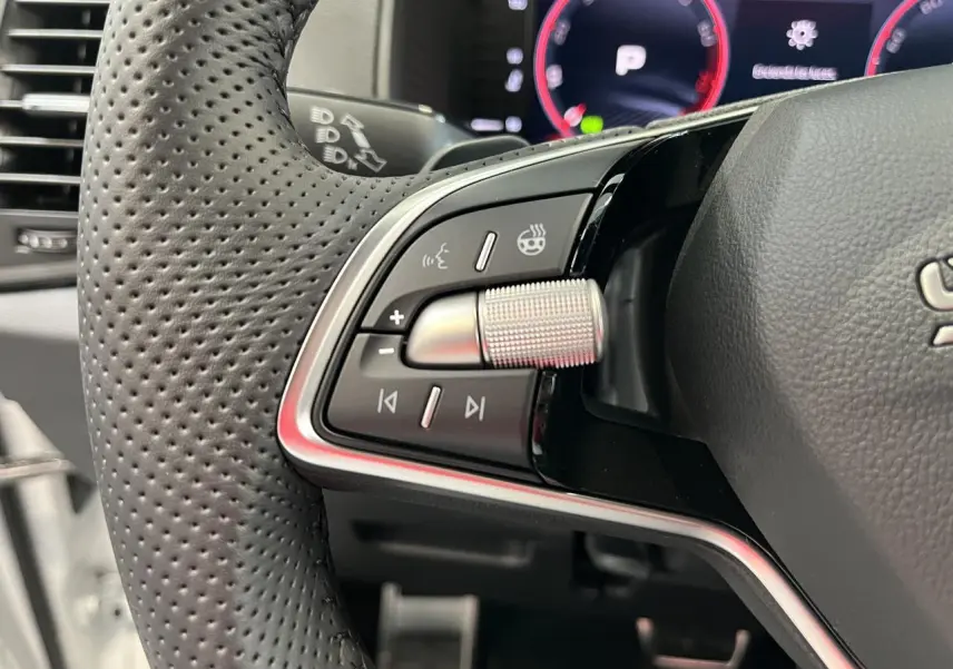 Gros plan sur les commandes multifonctions en aluminium du volant perforé noir du Skoda Karoq 2025.