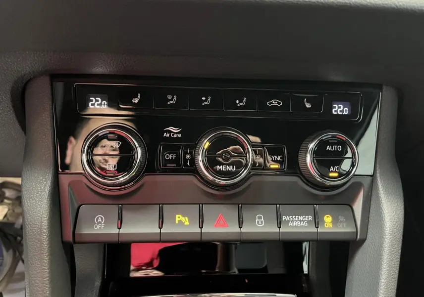 Détail de la console de climatisation automatique tri-zone du Skoda Karoq blanc, avec commandes digitales et boutons rétroéclairés.