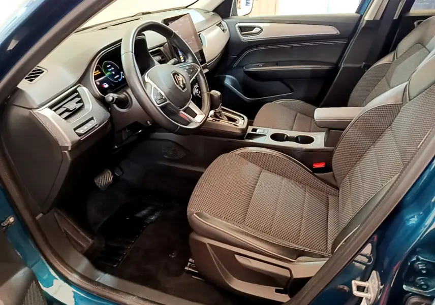 Vue intérieure côté conducteur de la Renault Arkana bleu, avec tableau de bord digital et sièges tissu gris.