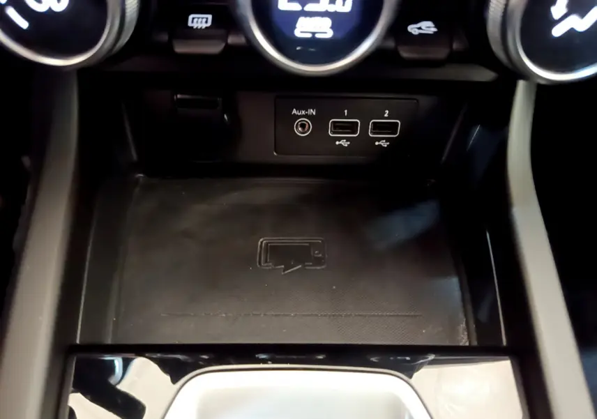 Gros plan sur la console centrale du Renault Arkana bleu, montrant les ports USB, prise Aux-IN et zone de recharge sans fil.