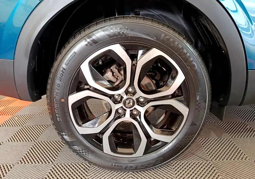 Gros plan sur la roue avant droite bleu métallisé du Renault Arkana Techno E-Tech avec jante alliage noire et argent.