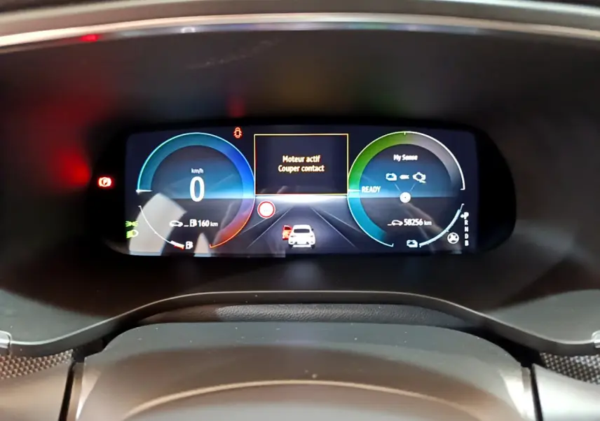 Vue rapprochée du tableau de bord numérique du Renault Arkana bleu, affichant la vitesse à 0 km/h et l'état moteur actif.