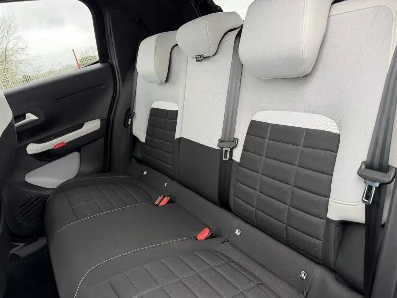 Vue intérieure de la banquette arrière de la Citroën C3 2025, avec sièges bicolores noir et gris clair.