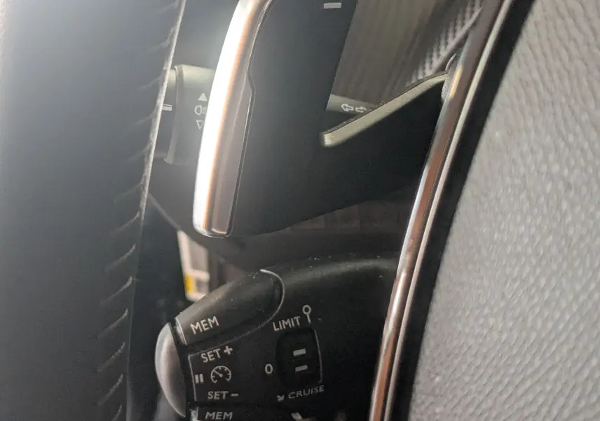 Gros plan sur la commande de régulateur de vitesse au volant du Peugeot 2008 noir 2024, finition allure.