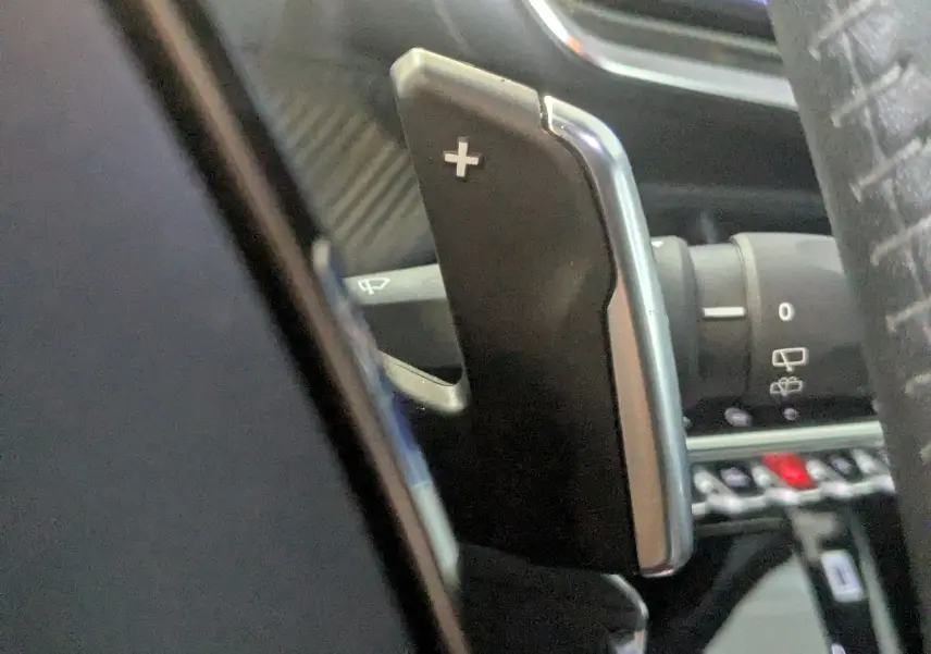Gros plan sur la palette de changement de vitesse "+" côté droit du volant dans l'habitacle d'une Peugeot 2008 noir.