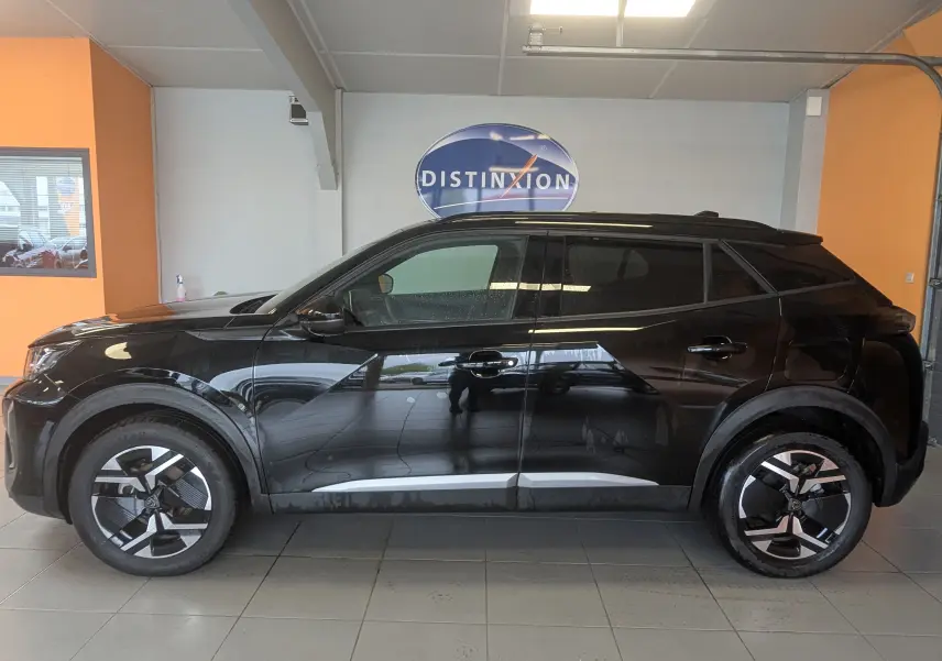 Peugeot 2008 noir 3/4 profil droit en intérieur, soulignant ses jantes bi-ton et lignes modernes.