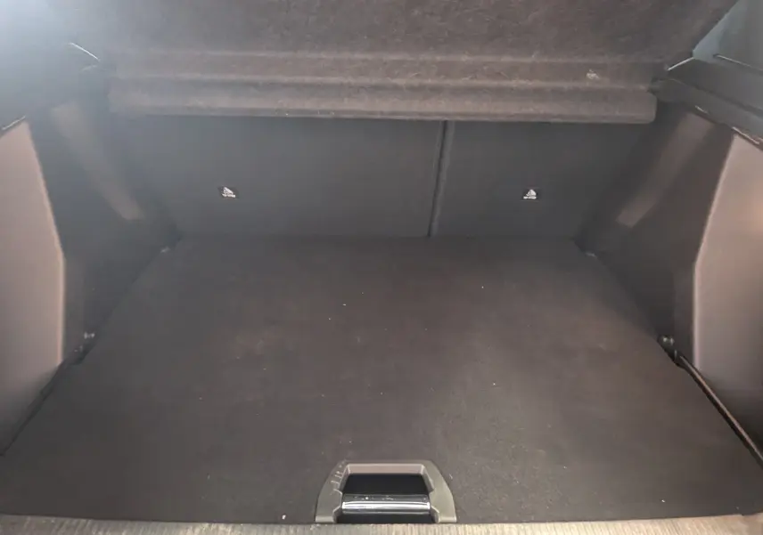 Coffre spacieux et vide de la Peugeot 2008 130ch eat8 allure 2024, vue intérieure arrière, revêtement noir.