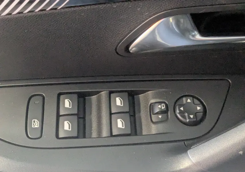 Gros plan sur les commandes des vitres et rétroviseurs côté conducteur d’un Peugeot 2008 noir 2024.