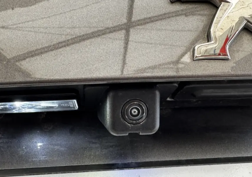 Gros plan sur la caméra de recul intégrée à la malle arrière gris foncé d'un Peugeot 2008.