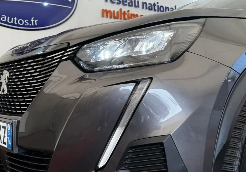 Gros plan sur l'avant droit gris foncé du Peugeot 2008 2022, mettant en valeur le phare LED et la calandre distinctive.