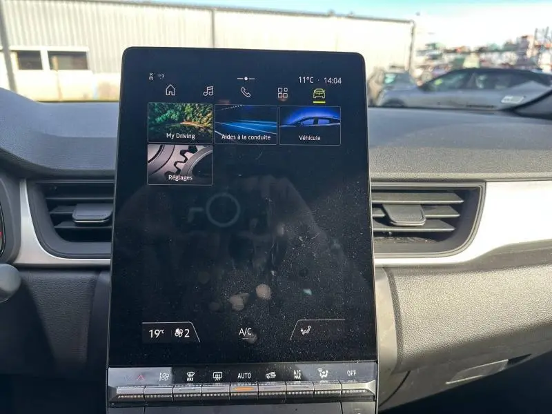 Écran tactile central du tableau de bord du Renault Captur 2025, avec commandes climatisation et aides à la conduite visibles.