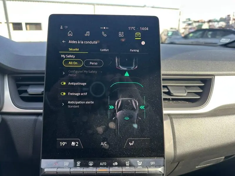 Écran tactile central du tableau de bord du Renault Captur 2025 affichant les aides à la conduite, entouré de la console noire et grise.