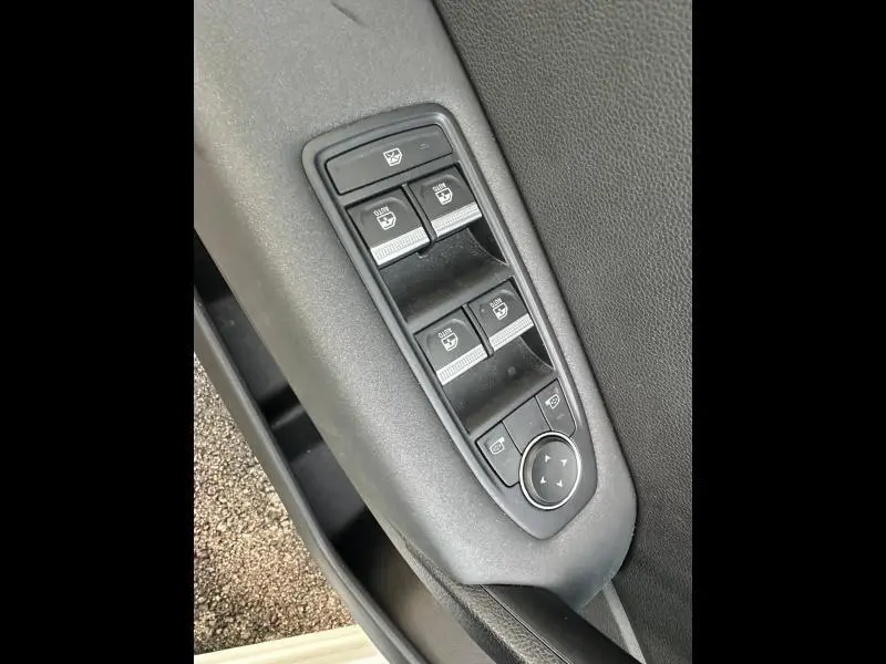 Gros plan sur les commandes des vitres électriques et réglages des rétroviseurs côté conducteur du Renault Captur blanc nacré.