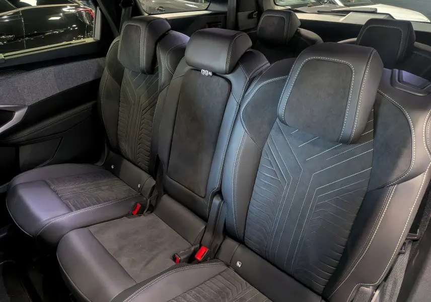 Vue intérieure sur la banquette arrière en cuir noir et alcantara du Peugeot 5008 Hybrid 145 GT 2025, avec surpiqûres contrastées.