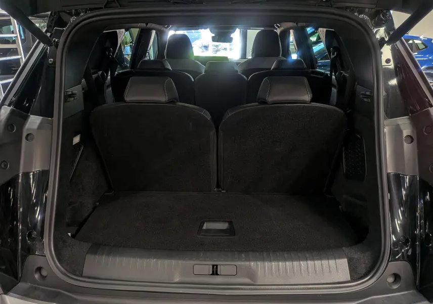 Vue arrière ouverte du coffre du Peugeot 5008 HYBRID 145 CH e-DCS6 GT noir Perla, montrant les sièges arrière et la capacité de chargement.
