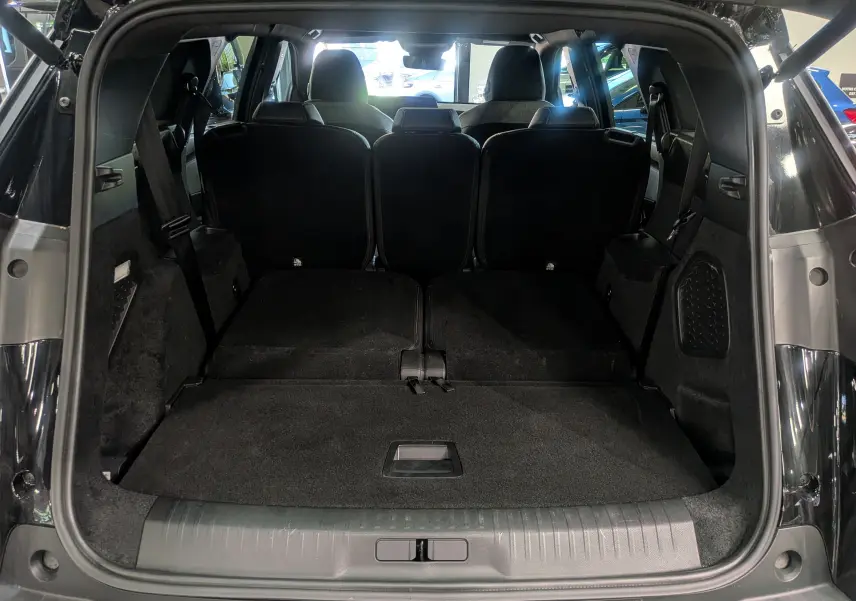 Vue arrière du coffre ouvert du Peugeot 5008 Hybrid 145 CH e-DCS6 GT noir Perla avec sièges rabattus offrant un grand espace de chargement.