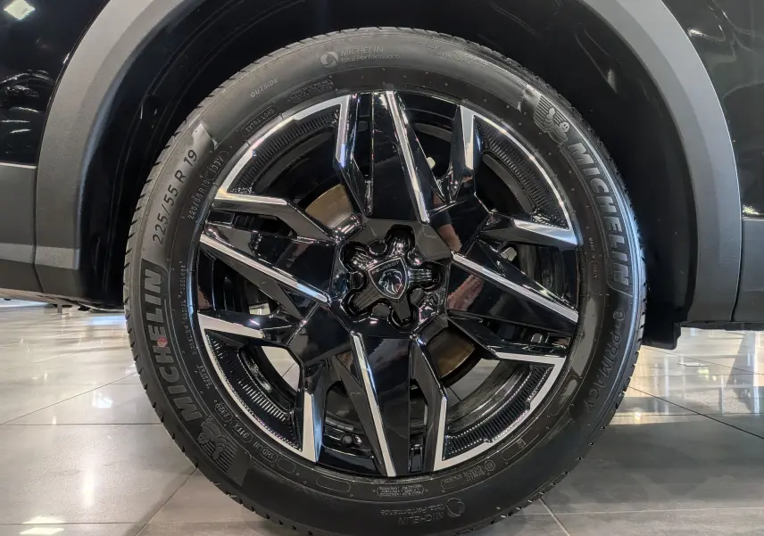 Gros plan sur la roue avant droite du Peugeot 5008 Hybrid 145 GT noir Perla avec jante alliage noir et inserts chromés.