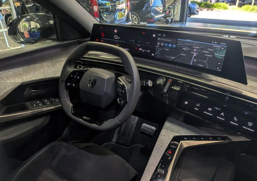Vue intérieure côté conducteur du Peugeot 5008 Hybrid 145 GT noir Perla, avec tableau de bord numérique panoramique et volant compact.