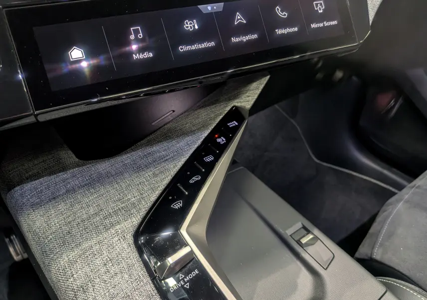 Vue rapprochée de la console centrale et écran tactile du Peugeot 5008 Hybrid 145 GT 2025 avec finition tissu gris et commandes tactiles.