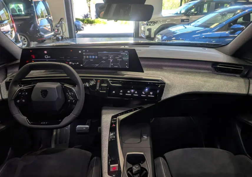 Vue intérieure frontale du tableau de bord du Peugeot 5008 Hybrid 145 GT 2025, avec écran tactile et volant compact noir.