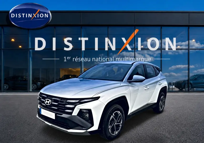 Hyundai Tucson blanc vu en 3/4 avant droit, avec calandre noire et jantes alliage 17 pouces distinctives.