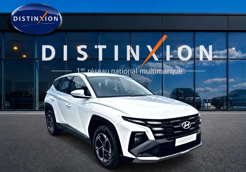 Hyundai Tucson blanc en 3/4 avant droit, avec calandre noire distinctive et jantes alliage 17 pouces.