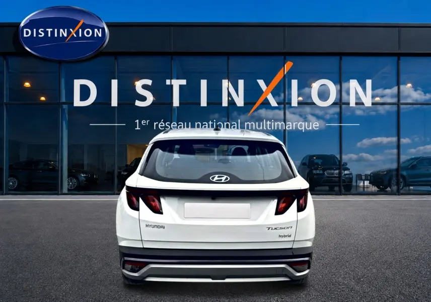 Vue arrière d'un Hyundai Tucson blanc hybride 2026, avec feux arrière sombres et logo Hyundai visible.