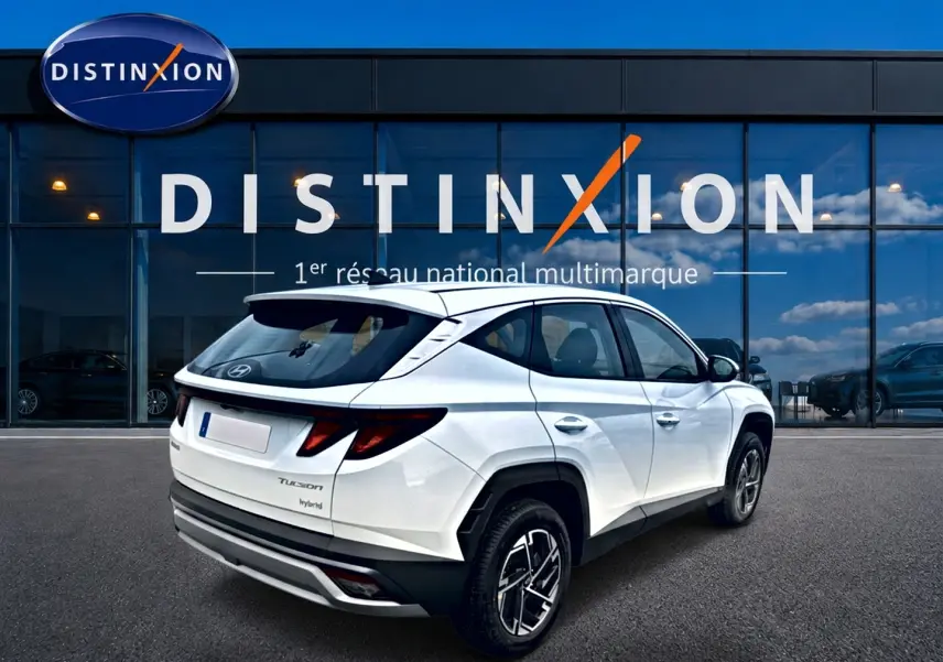 Hyundai Tucson hybride blanc en 3/4 arrière droit, avec jantes alliage et feux arrière LED distinctifs.
