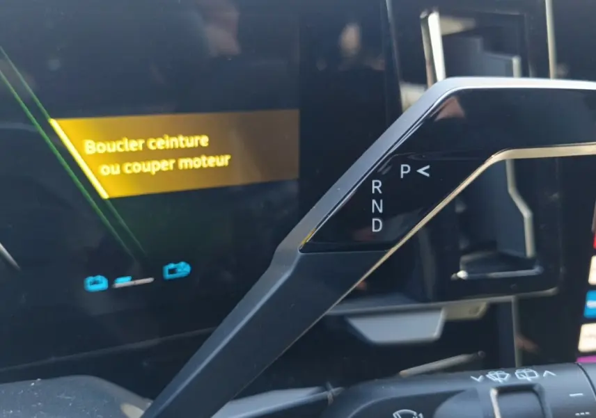 Détail intérieur du levier de vitesses automatique et écran multifonctions avec message d'alerte sur Renault Austral blanc.
