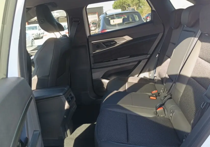 Vue intérieure côté droit des sièges arrière noirs du Renault Austral Esprit Alpine blanc, avec habillage de porte et console centrale visibles.