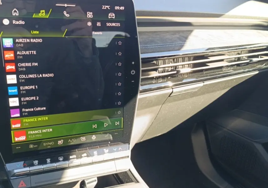 Intérieur du Renault Austral esprit Alpine blanc, vue sur l'écran tactile central et la planche de bord avec finition noire et surpiqûres bleues.