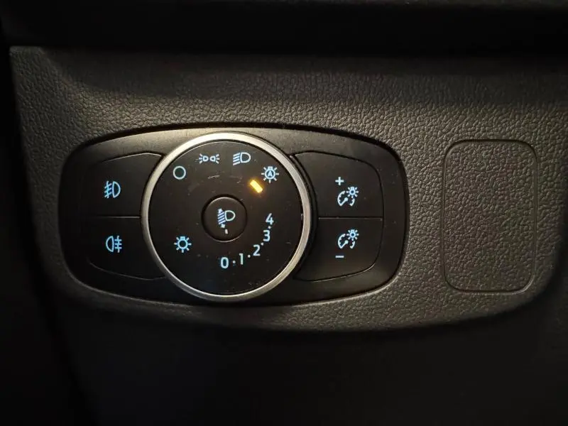 Gros plan sur le bouton de réglage des phares avec éclairage bleu dans une Ford Focus noir Agate 2021 Titanium X