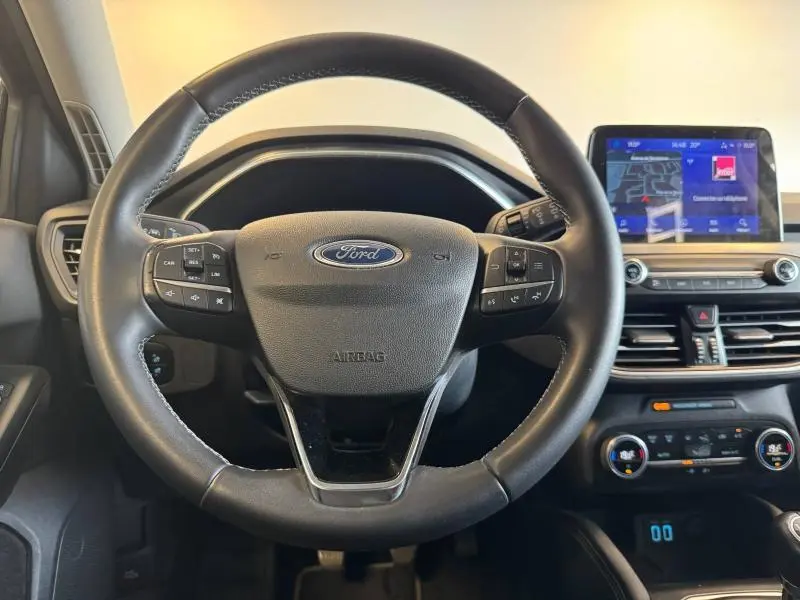 Vue rapprochée du volant cuir multifonction de la Ford Focus 2021 avec tableau de bord et écran tactile GPS visible.