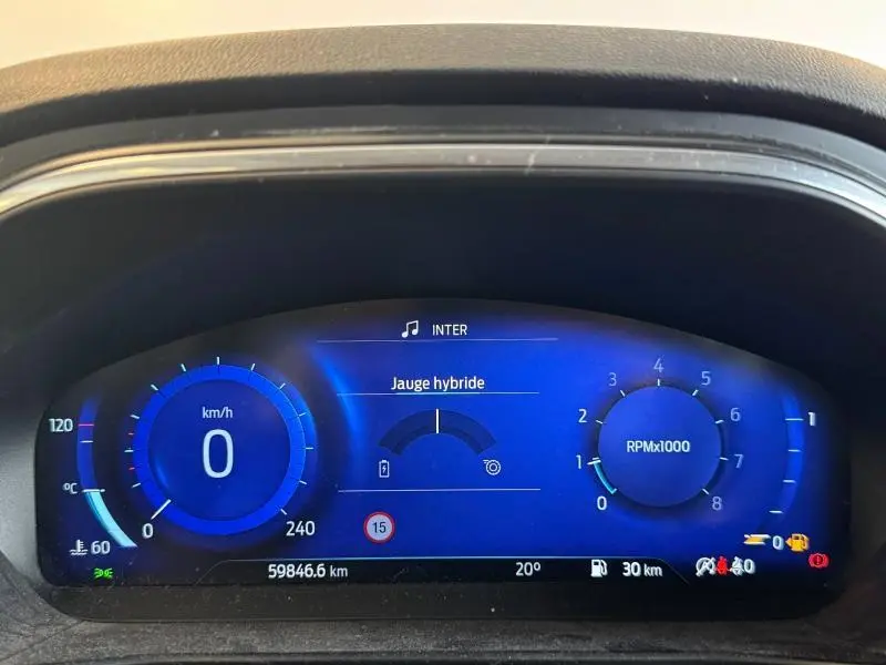 Tableau de bord numérique bleu de la Ford Focus 2021 affichant vitesse, compte-tours et jauge hybride.