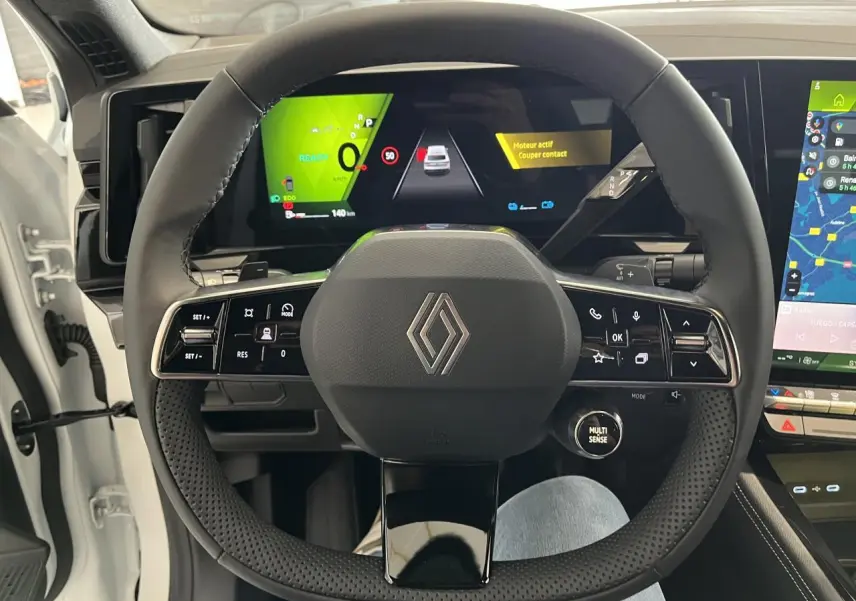 Vue intérieure centrée sur le volant noir perforé de la Renault Rafale blanche avec tableau de bord numérique et écran tactile.