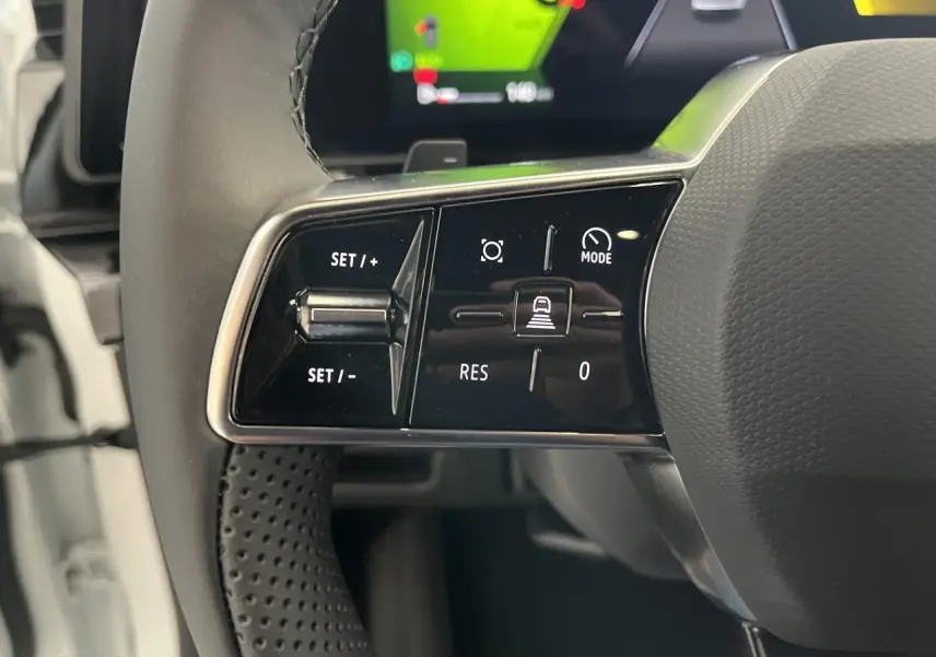 Gros plan sur les commandes à gauche du volant textile refined d'une Renault Rafale blanche, affichage numérique en arrière-plan.