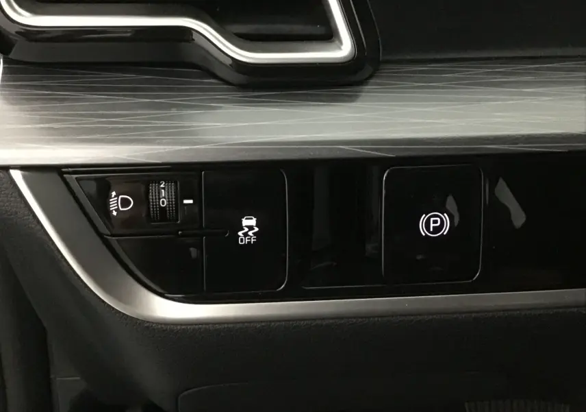 Gros plan sur les commandes d'assistance et frein à main électronique du Kia Sportage gris Sirius 2025.