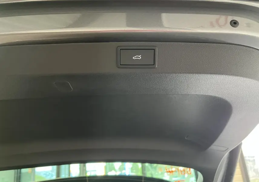 Bouton d'ouverture électrique du hayon sur la face intérieure du coffre d'un SUV SKODA KAROQ gris.