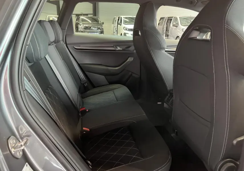 Vue intérieure côté gauche des sièges arrière noirs avec surpiqûres blanches du Skoda Karoq gris 2025 Sportline.