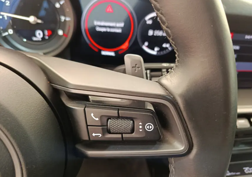 Gros plan sur le volant cuir noir de la Porsche 911 Carrera 4S 2019 avec commandes multifonctions et palettes au volant.