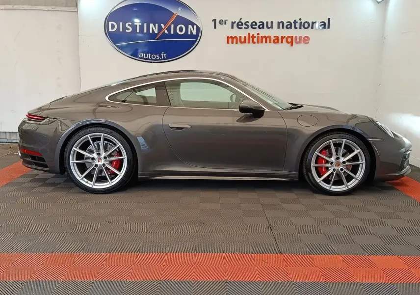 Vue de profil côté gauche d'une Porsche 911 Carrera 4S Coupé gris foncé avec jantes sport et étriers rouges.